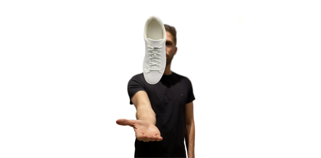 Junger Mann lässt einen Sneaker über der Hand schweben. Die Sneaker sind mit Schnürlos ORIGINAL Schnürsenkel und einer silbernen Metallkapsel (Schnürlos CAPS) ausgestattet.