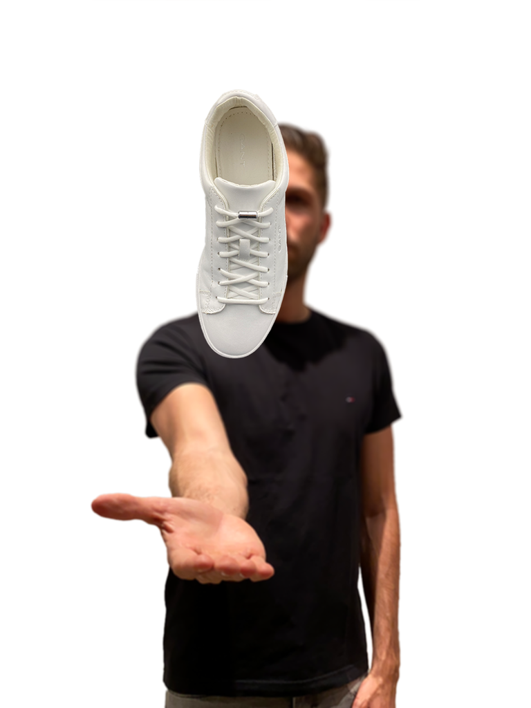 Junger Mann lässt einen Sneaker über der Hand schweben. Die Sneaker sind mit Schnürlos ORIGINAL Schnürsenkel und einer silbernen Metallkapsel (Schnürlos CAPS) ausgestattet.